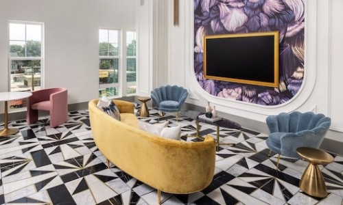 Modern resident lounge with yellow velvet couch and geometric tile flooring